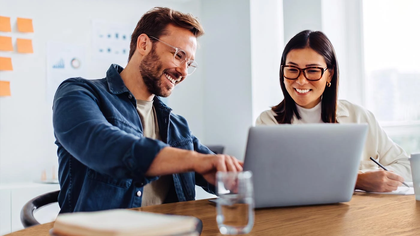 Zwei Personen planen Social-Media-Beiträge am Laptop