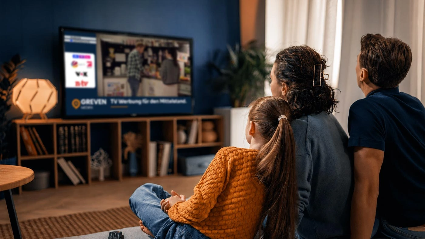 Familie sieht abends gemeinsam fern im Wohnzimmer