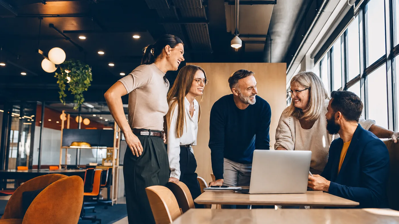 Fünf Personen besprechen ein Projekt am Laptop in einem hellen Büro