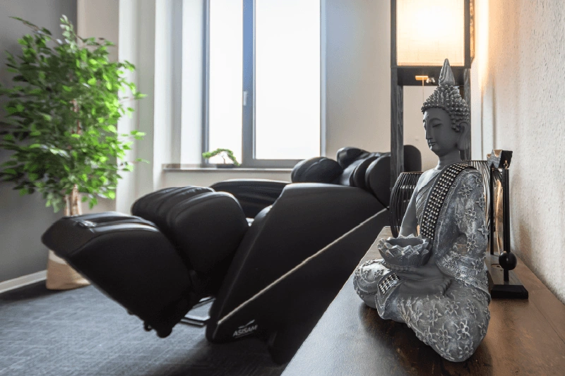 Massagesessel am Fenster neben einer Buddha-Figur
