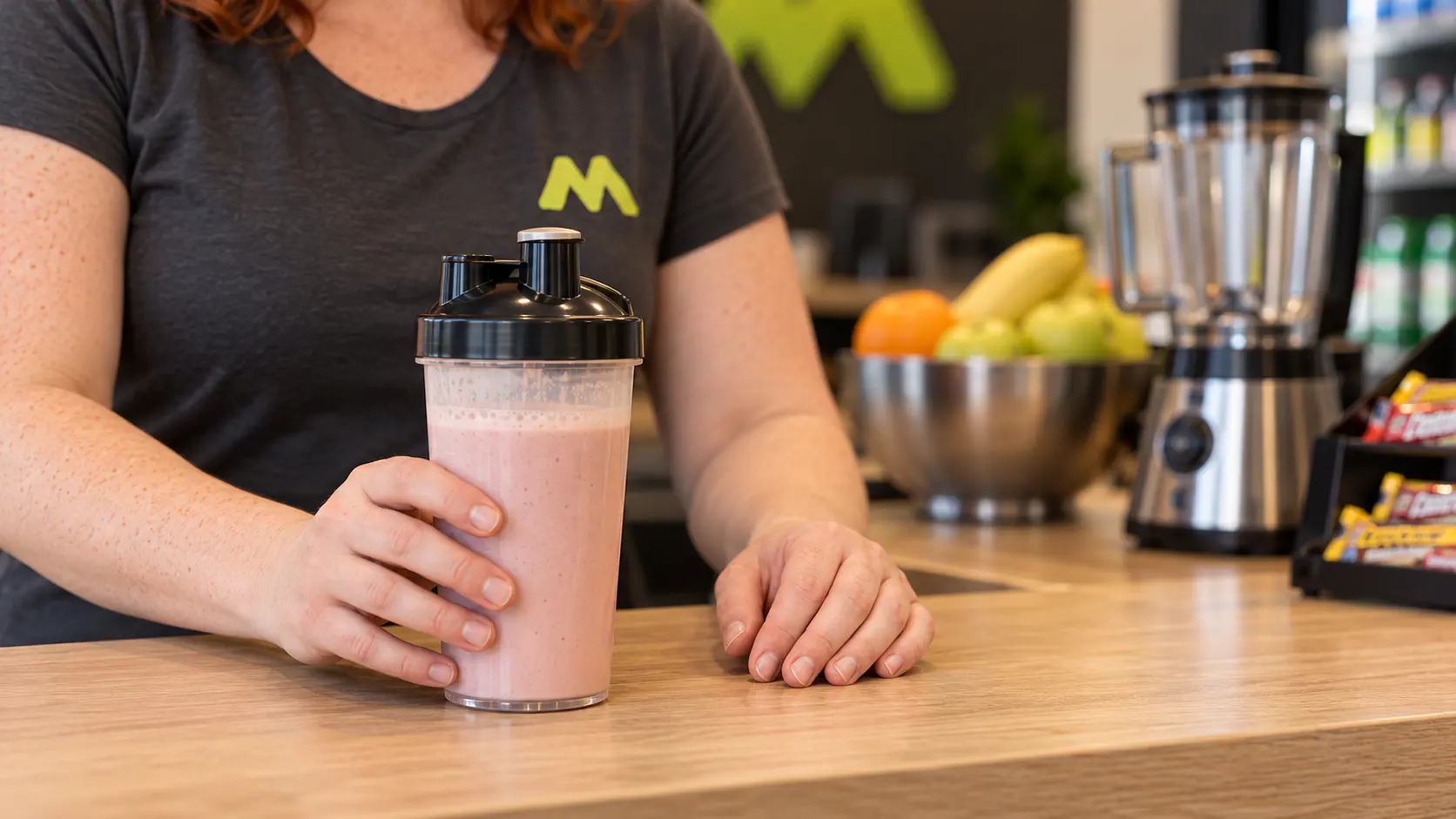 Fenjas Hände stellen einen fertigen Shake mit schwarzem Deckel auf die Theke.